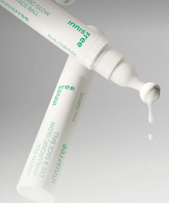 Décris l'image en français : INNISFREE Green Tea Hyaluronic Glow Eye & Face Ball, tube crème vert sur fond clair, gouttes.