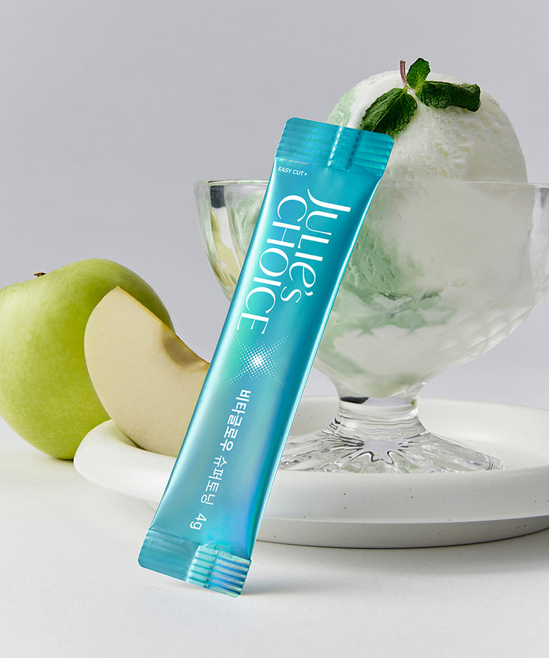 Décris l’image en français : JULIE'S CHOICE Vita Glow Super Toning de la marque, tube bleu sur fond blanc, pomme verte.