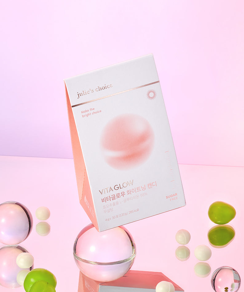 JULIE'S CHOICE Vita Glow Whitening Candy, boite et bonbons sur fond rose pastel, marque visible, décor cosmétique.