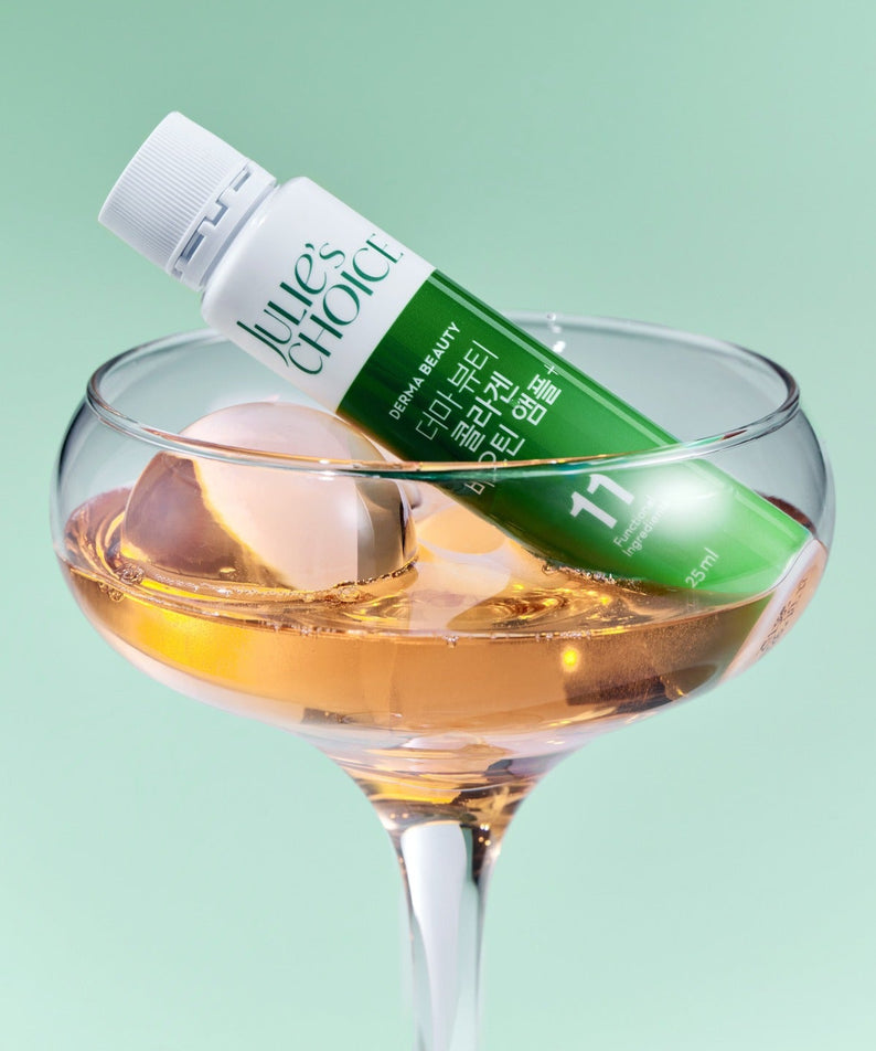 JULIE'S CHOICE Derma Beauty Collagen Biotin Ampoule 25ml dans un verre élégant avec des glaçons, sur fond vert.