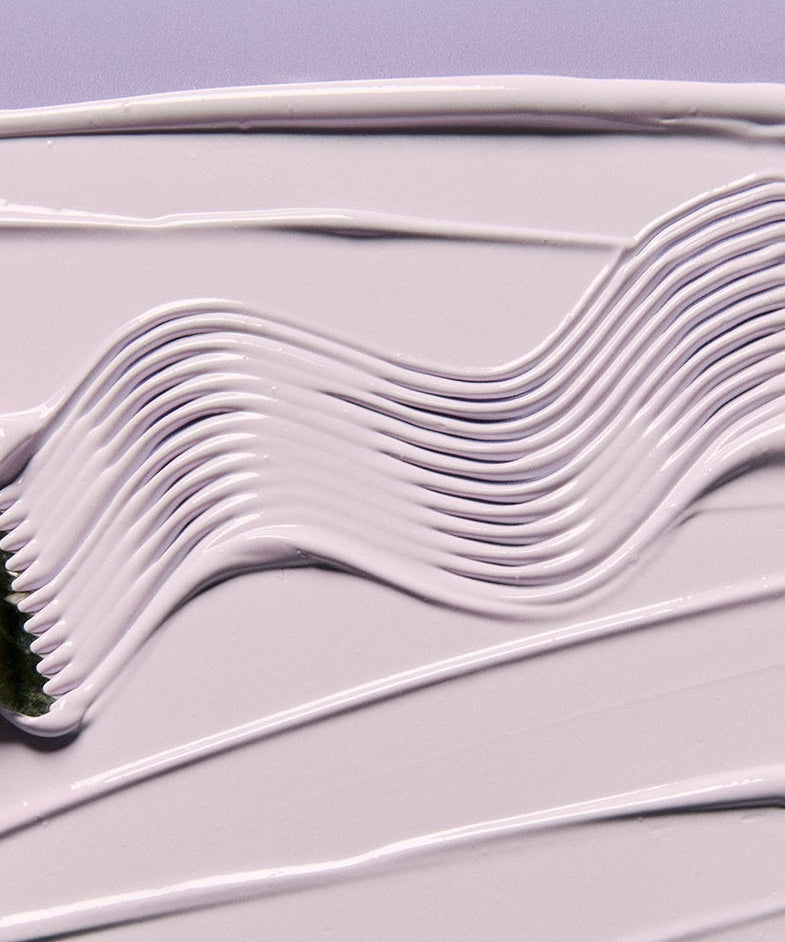 Décris l'image en français : JUMISO Niacinamide 3 Plus Tone-Up Sunscreen 40ml, texture crème blanche étalée sur fond violet.