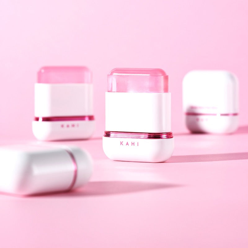 KAHI Velvet Glow Sun Stick 13.5g, stick solaire KAHI sur fond rose pastel, flacons cosmétiques en arrière-plan