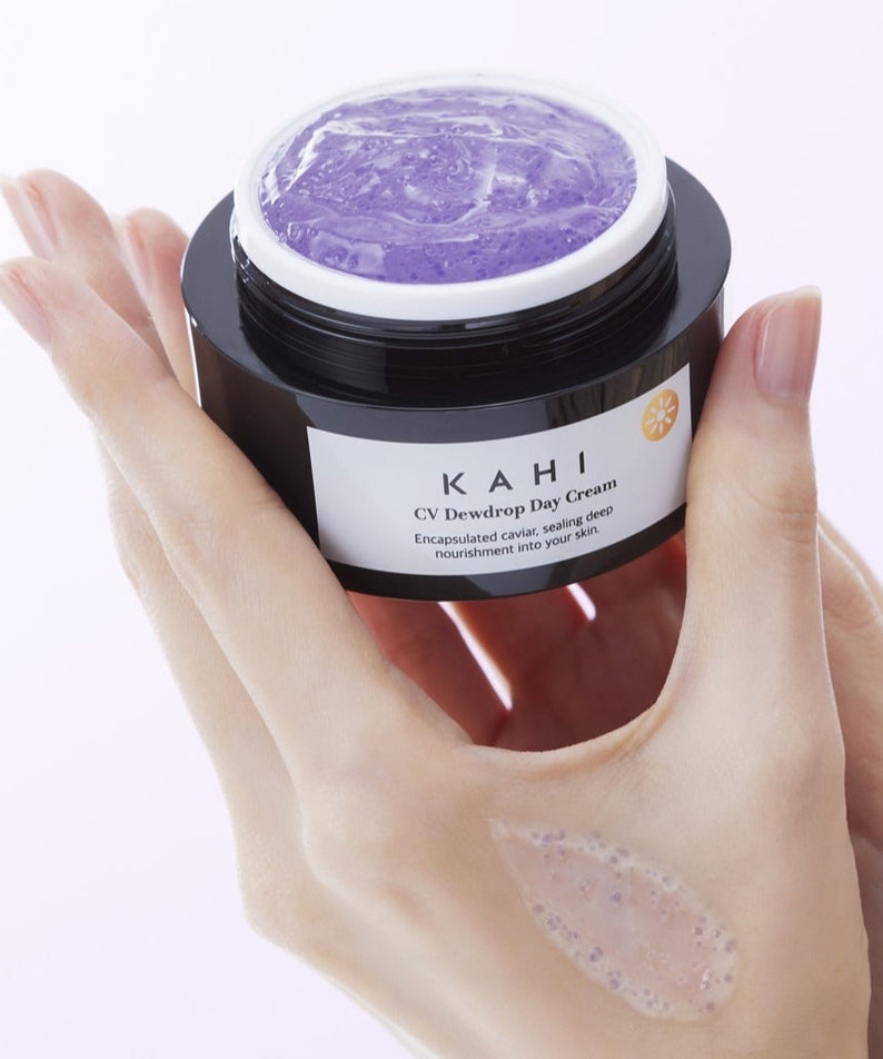 Pot de KAHI CV Dewdrop Day Cream 50ml tenu par une main, texture crémeuse visible sur la peau, soulignant l'hydratation du produit.