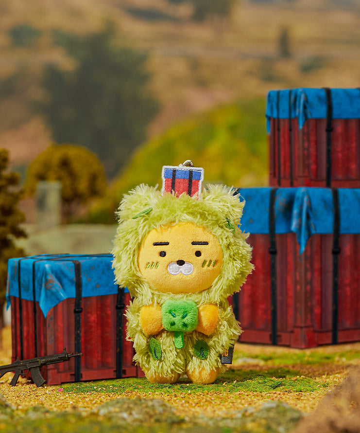 KAKAO FRIENDS Battleground X Friends Keychain Doll, personnage jaune avec accessoire, décor extérieur de ferme en fond.