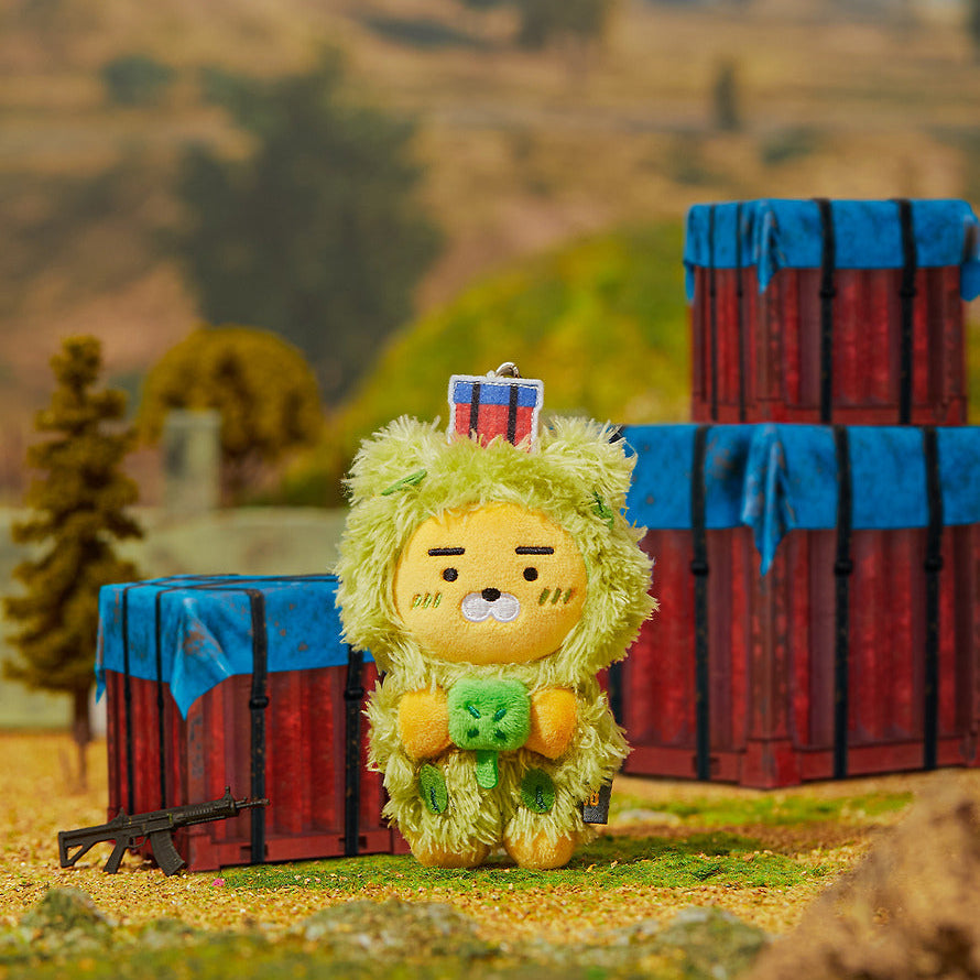 KAKAO FRIENDS Battleground X Friends Keychain Doll, personnage jaune avec accessoire, décor extérieur de ferme en fond.