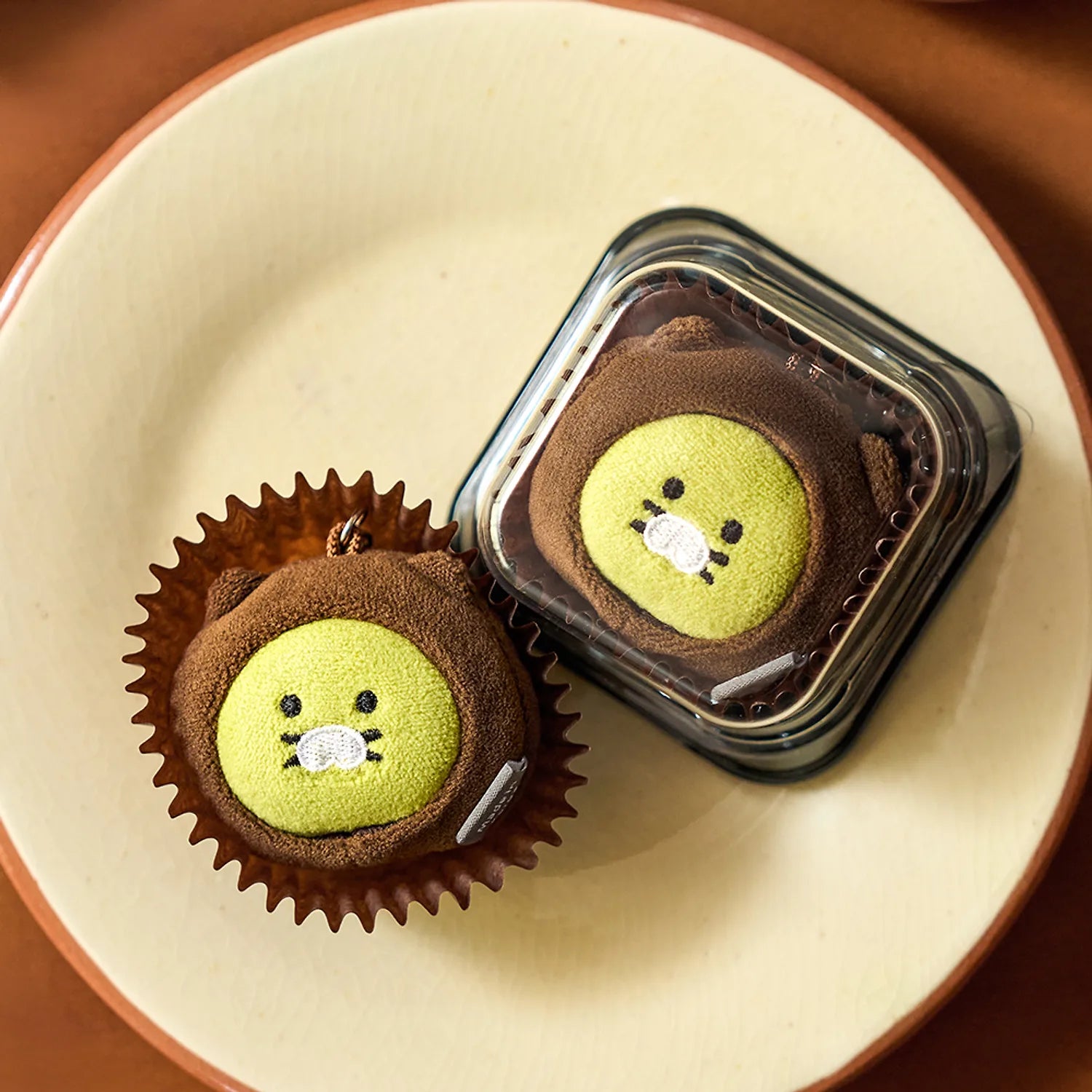 KAKAO FRIENDS Dujjonchun keychain doll : deux personnages en cupcake, présentés sur une assiette, ambiance dessert.