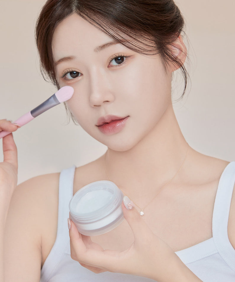 Femme utilisant le KEEP IN TOUCH Mini Pore Eraser Powder avec un pinceau de maquillage. Produit de beauté pour un teint lisse.