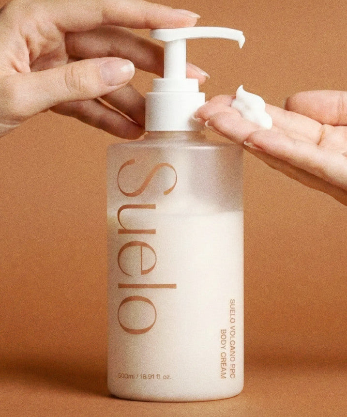 SUELO Volcano Body Slimming Anti-Puffiness Cream 500ml : pompe dose, mains appliquant la crème sur peau, bouteille SUELO, visuel produit.