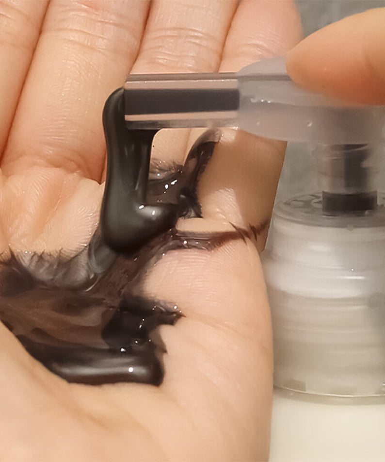 Shampoo LADOR ASH Silver 300ml sur la paume de la main, concentré noir intense pour un soin capillaire éclatant.