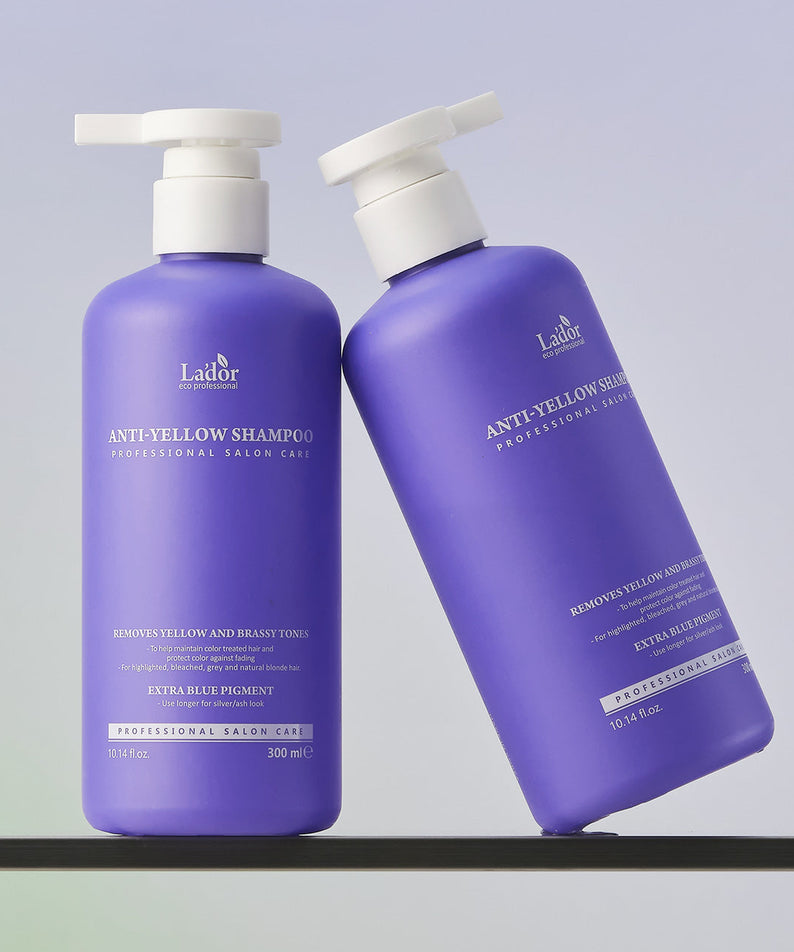 Deux bouteilles de LADOR Anti-Yellow Complement Tary Shampoo 300ml sur une étagère, shampooing spécial pour cheveux blonds.
