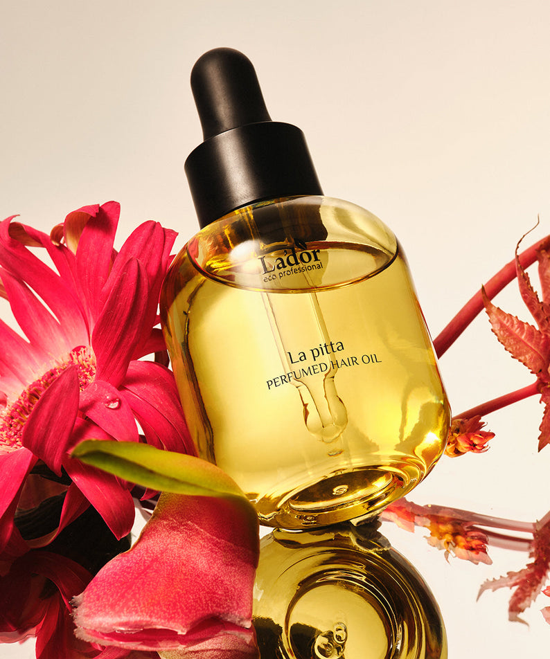 LADOR Perfume Hair Oil 30ml avec fleurs colorées en arrière-plan, huile parfumée pour cheveux, flacon de 30ml en focus.