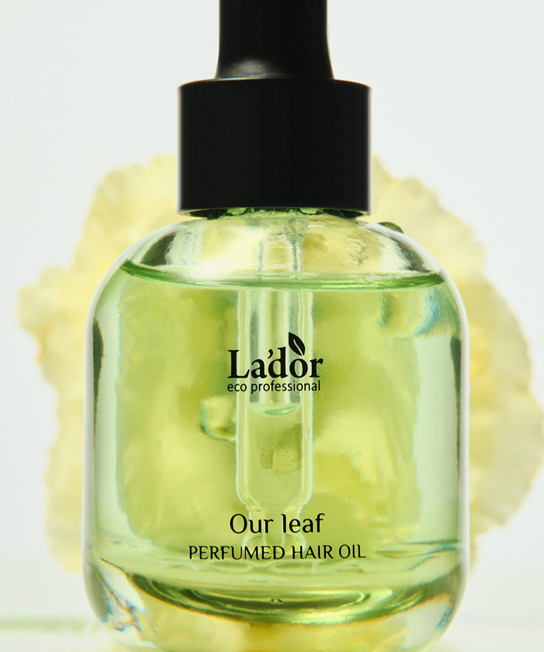 Flacon de LADOR Perfume Hair Oil 30ml avec huile parfumée sur fond de fleurs.