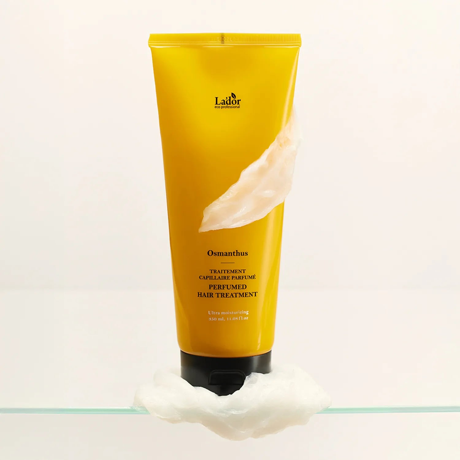 LADOR Perfume Hair Treatment 380ml de Lador, tube jaune posé sur coton, contexte blanc minimaliste.