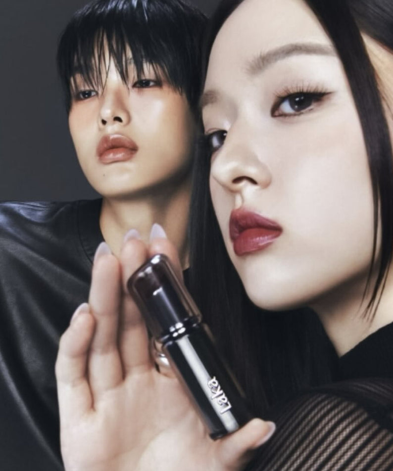 LAKA Devillip, maquillage par LAKA : deux modèles en studio tenant un rouge à lèvres, fond sombre, éclairage dramatique.