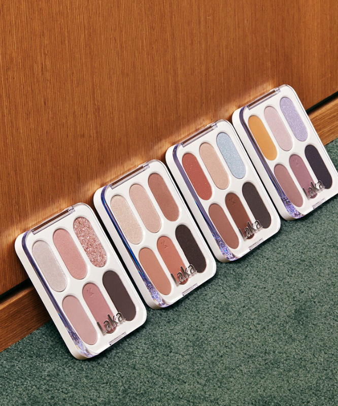 Palette d'ombres à paupières LAKA Forever 6 Eye Palette alignées contre un mur, offrant une gamme de couleurs variées pour un maquillage parfait.