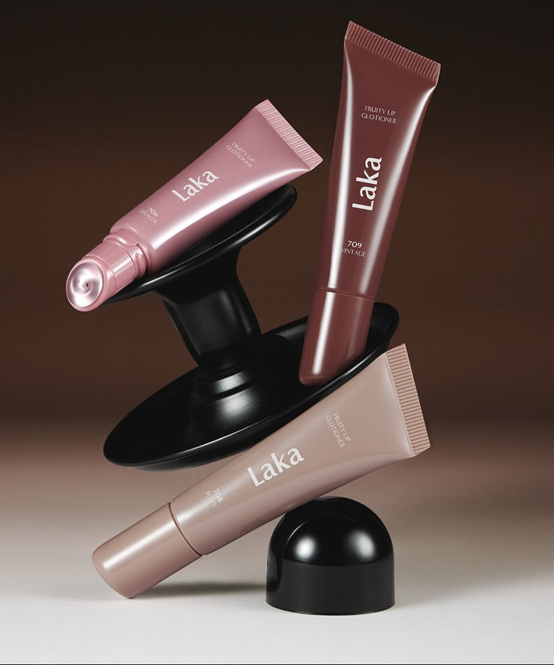 Produits LAKA Fruity Lip Glossionner disposés artistiquement, mettant en valeur leurs designs élégants et variés en teintes naturelles.