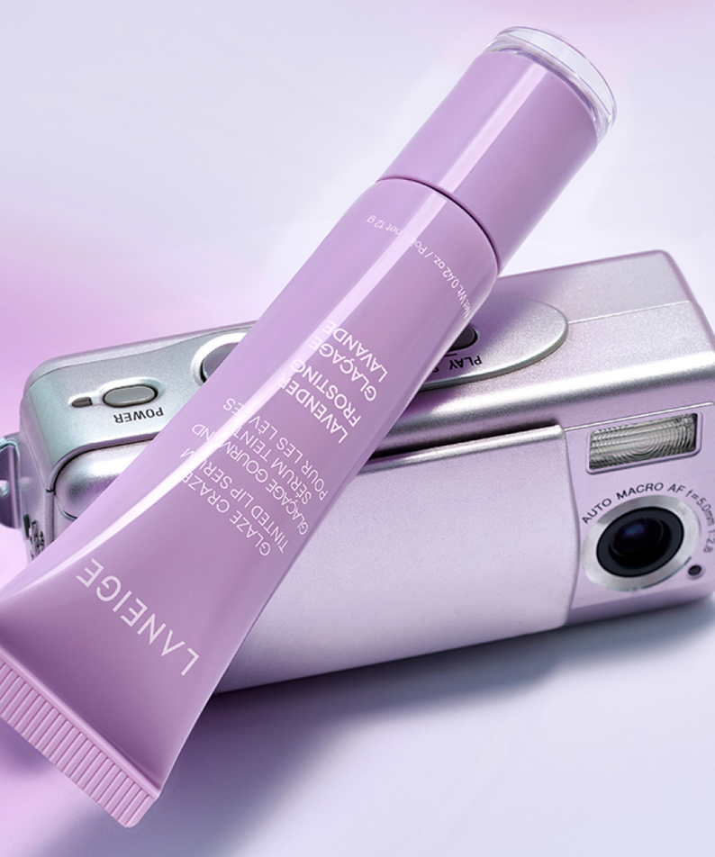 LANEIGE Glaze Craze Tinted Lip Serum, tube violet sur fond pastel avec accessoires maquillage, marque LANEIGE, contexte visuel
