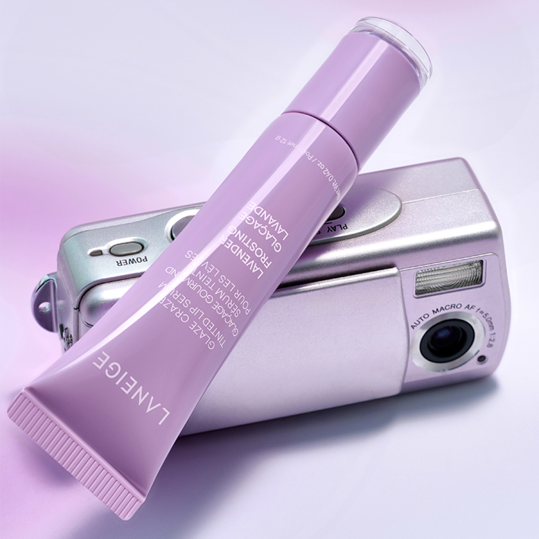 LANEIGE Glaze Craze Tinted Lip Serum, tube violet sur fond pastel avec accessoires maquillage, marque LANEIGE, contexte visuel