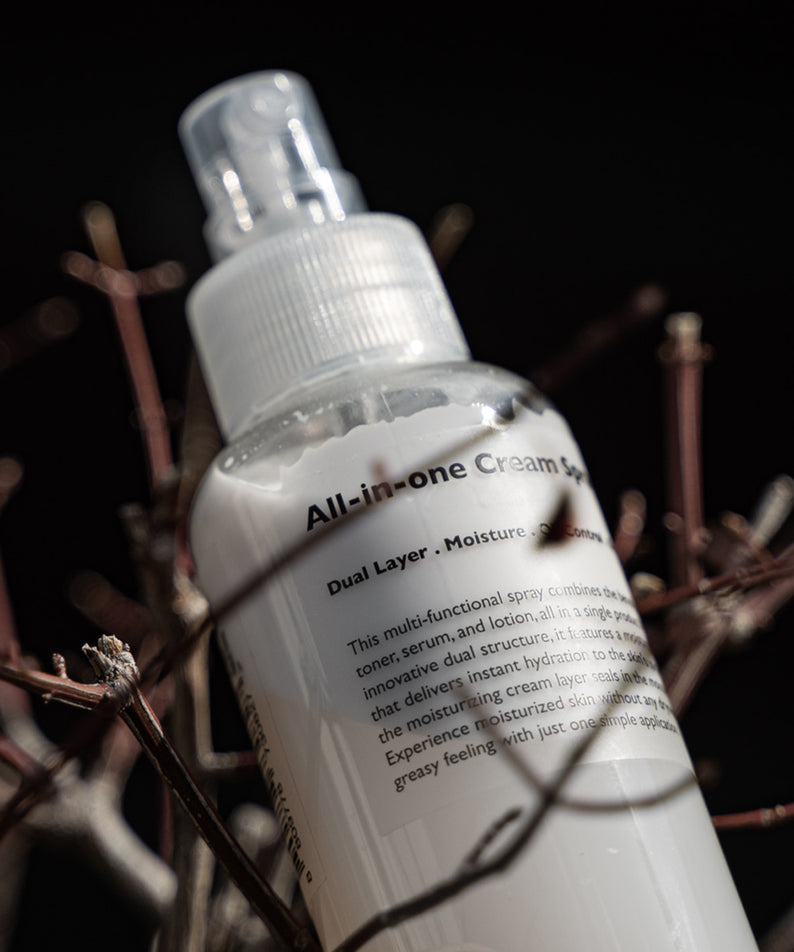 LAZY SOCIETY All-in-One Cream Spray 120ml, spray crème en gros plan sur tiges, style photo studio sombre