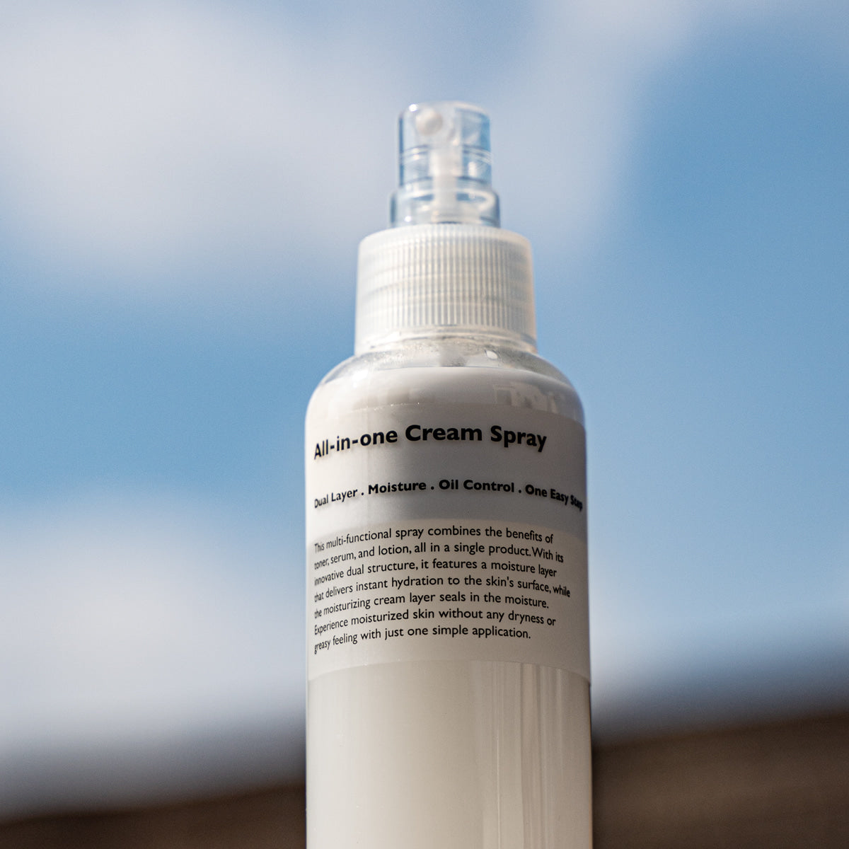 LAZY SOCIETY All-in-One Cream Spray 120ml, bouteille crème spray sur fond bleu ciel, produit beauté de la marque.