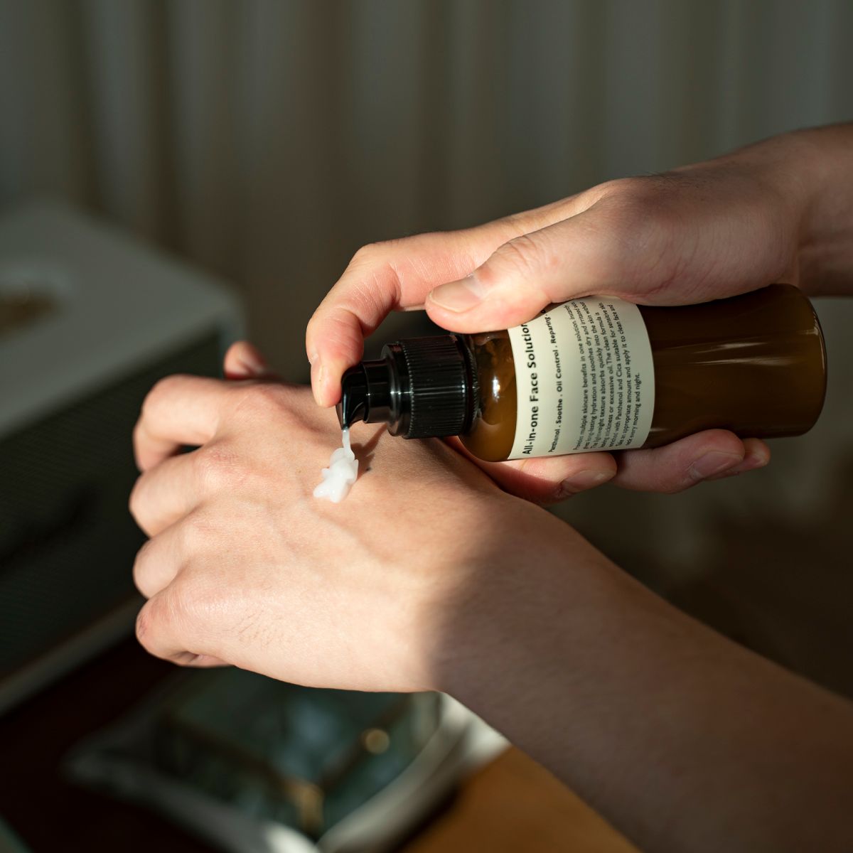 LAZY SOCIETY All-in-One Face Solution 150g : application de crème sur la main, marque au flacon, contexte salle de soins.