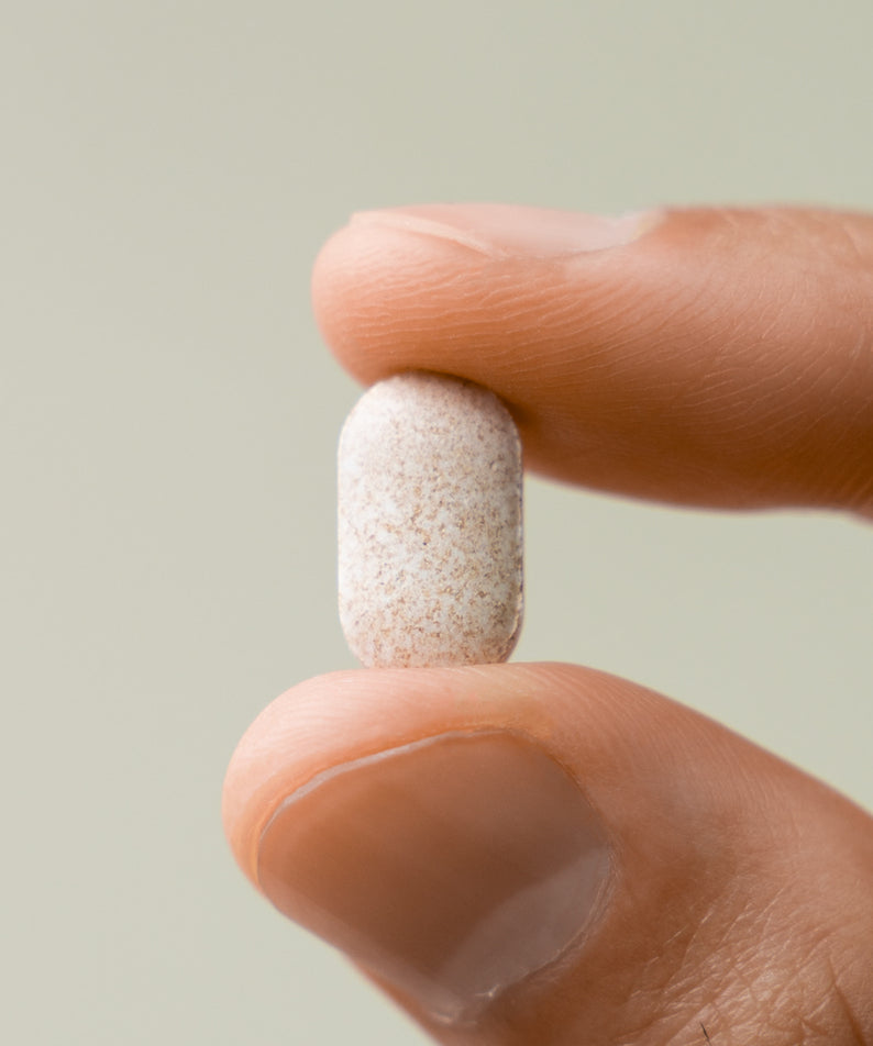 LAZY SOCIETY Biotin Essentail Wholesale : capsule de biotine tenue par un doigt, fond clair, marque en contexte cosmétique.