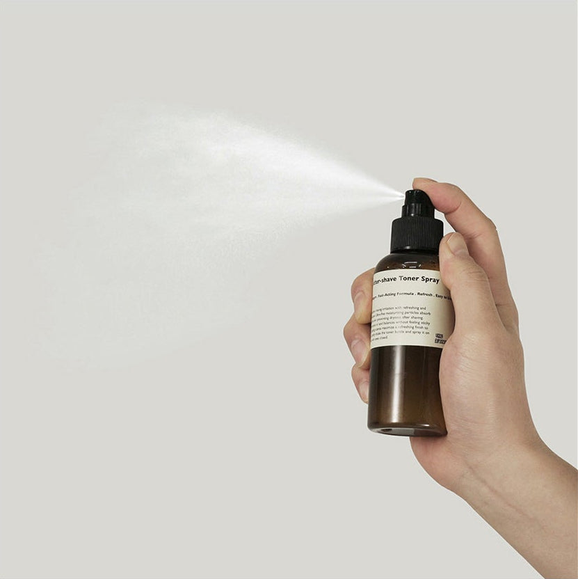 LAZY SOCIETY Cica Aftershave Toner Spray 120ml, main tenant le spray sur fond clair, produit beauté apaisant