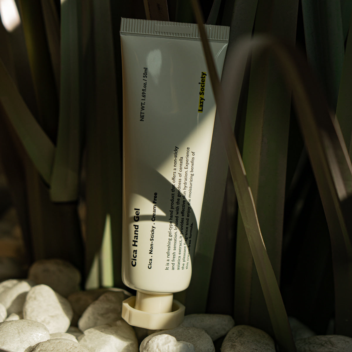 LAZY SOCIETY Cica Hand Gel 50ml, tube sur galets et herbes, ambiance naturelle, marque visible en contexte spa