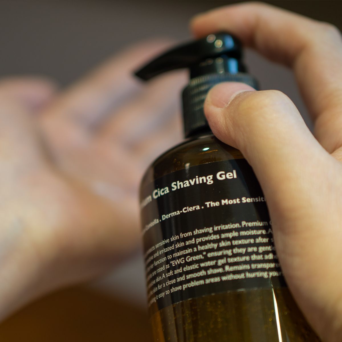 LAZY SOCIETY Premium Cica Shaving Gel 300ml : flacon en main, gel de rasage à la cica, salle de bain floue.