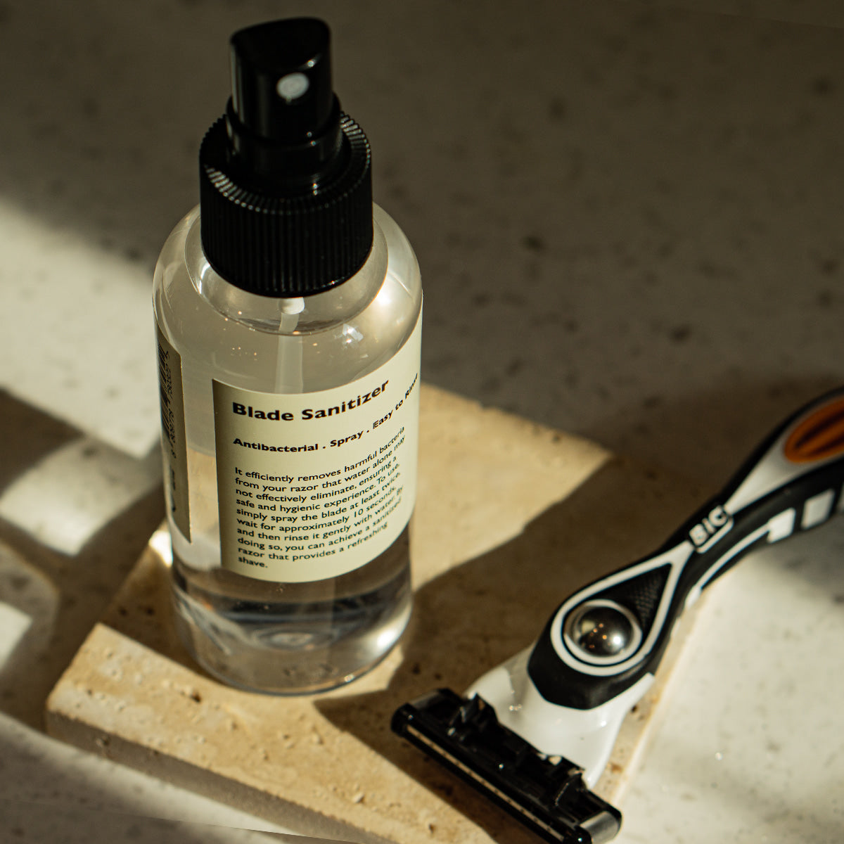 LAZY SOCIETY Razor Blade Sanitizer 120ml, spray désinfectant pour lame, bouteille noire sur lavabo avec rasoir, contexte salle d’eau