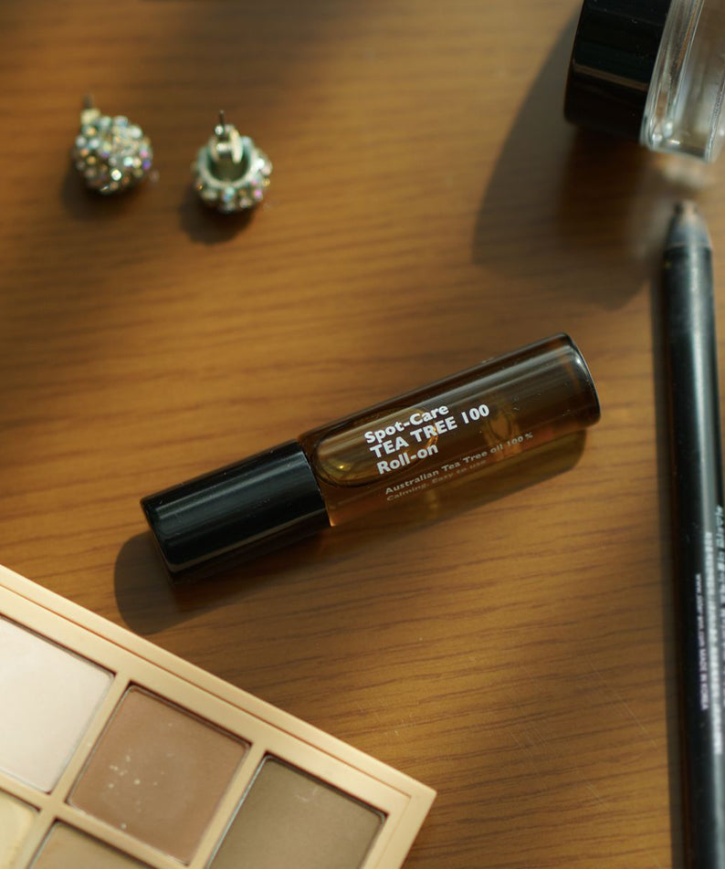 LAZY SOCIETY Spot Care Tea Tree 100 Roll on 5.5ml sur bureau, flacon roll-on près maquillage; marque en évidence.