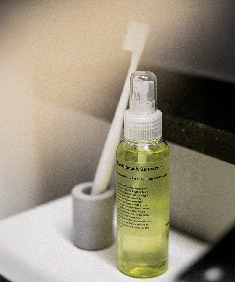 LAZY SOCIETY Toothbrush Sanitizer 100ml : flacon vert dans une salle de bain, brosse et flacon sur plan de travail.