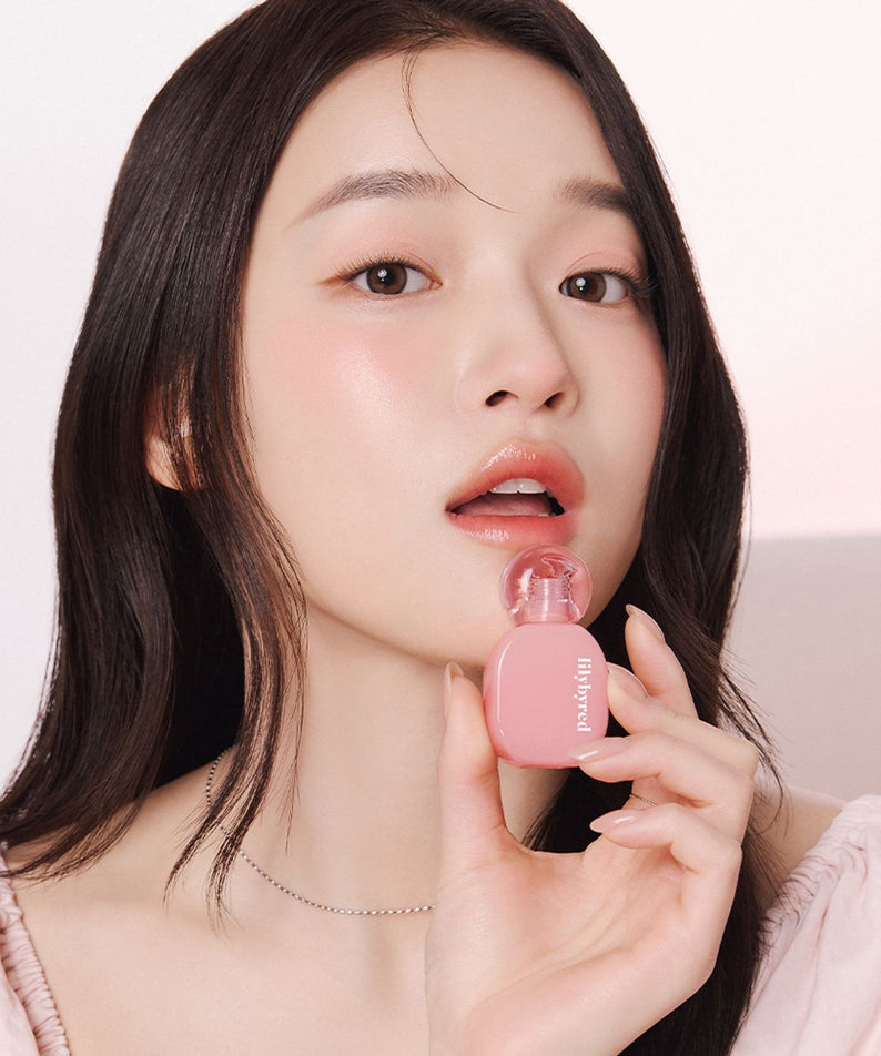LILYBYRED Balming Dewy Tint de la marque LILYBYRED, sur une femme tenant un baume teinté, fond clair, gros plan.
