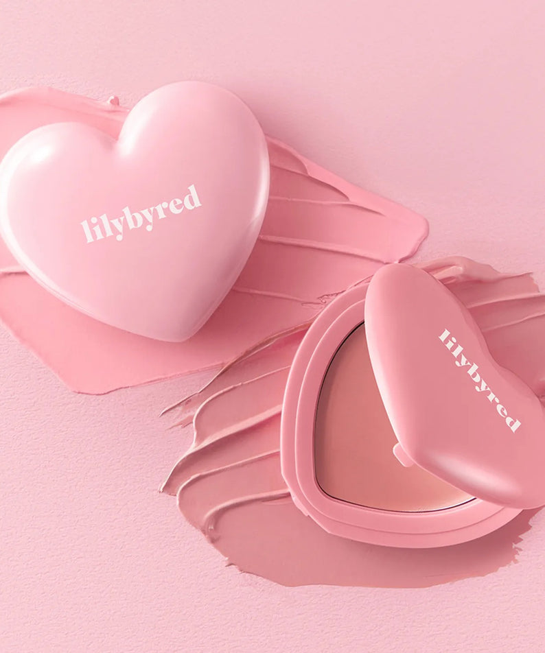 LILYBYRED Love Beam Cheek Balm, la marque sur un packaging cœur rose, maquillage sur fond rose pastel