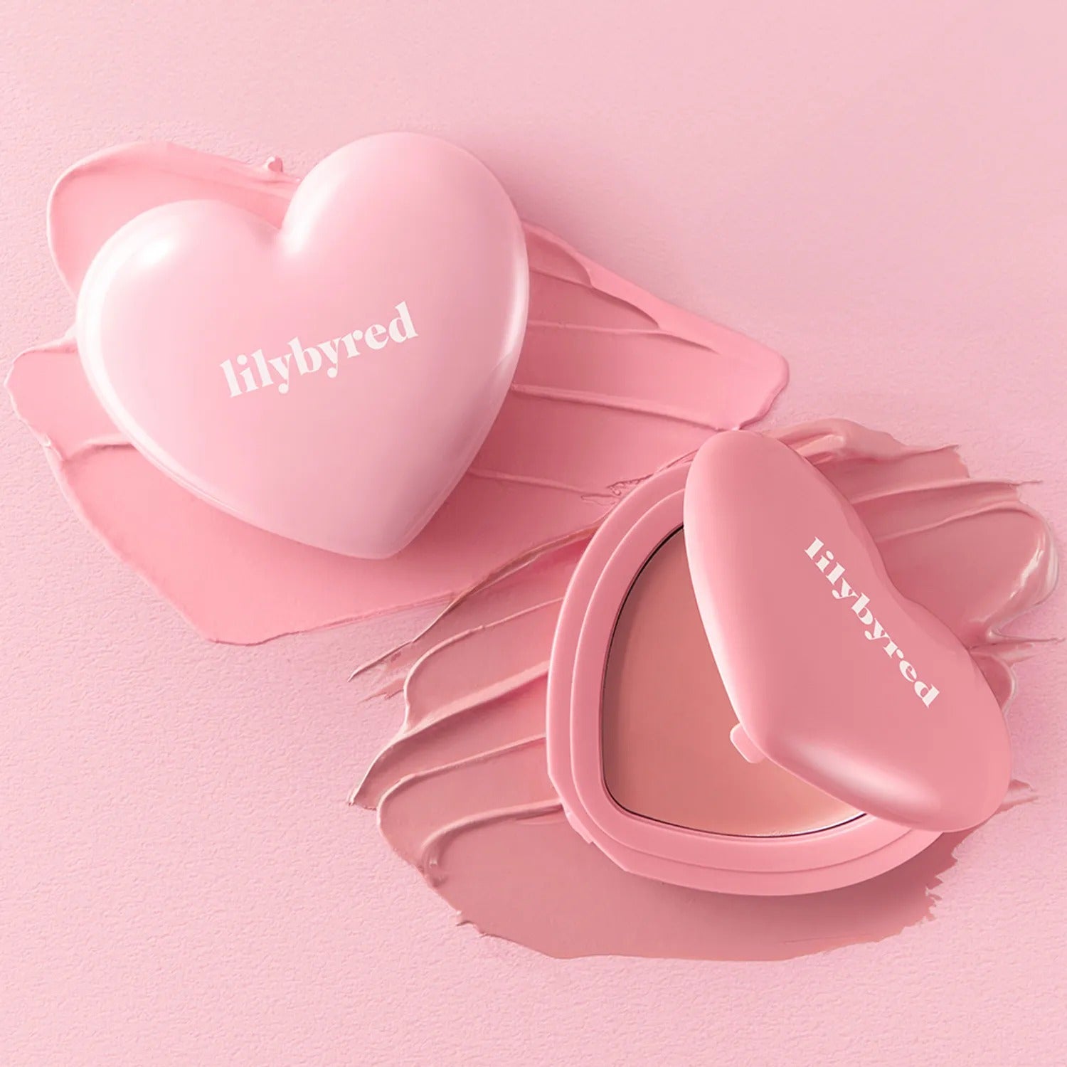 LILYBYRED Love Beam Cheek Balm, la marque sur un packaging cœur rose, maquillage sur fond rose pastel