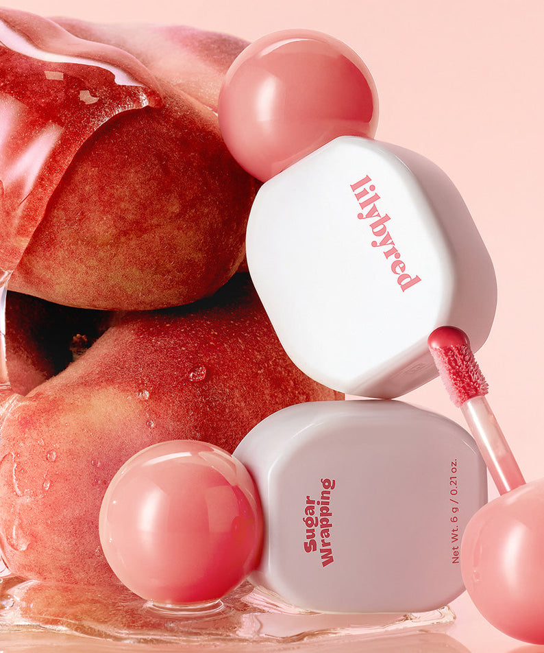 LILIBYRED Sugar Wrapping Tint Gloss avec texture fruitée, brillant à lèvres hydratant et intense, emballage élégant, pêche en arrière-plan.