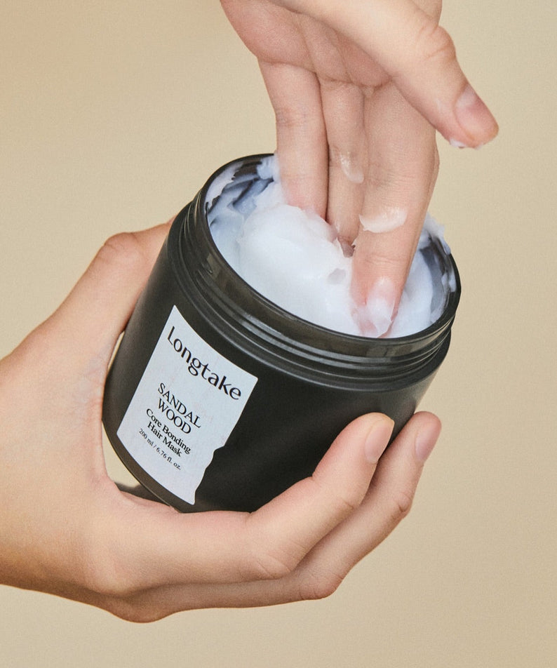 LONGTAKE Core Bonding Perfume Hair Mask Hair Pack 200ml, pot noir sur mains, texture crème blanche, ambiance beige.