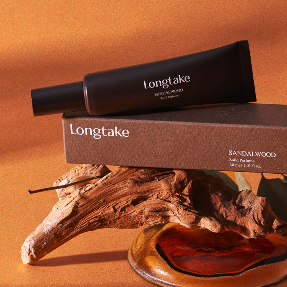 LONGTAKE Solid Perfume 30ml en stick sur fond beige, flacon Longtake et bois de santal en contexte visuel