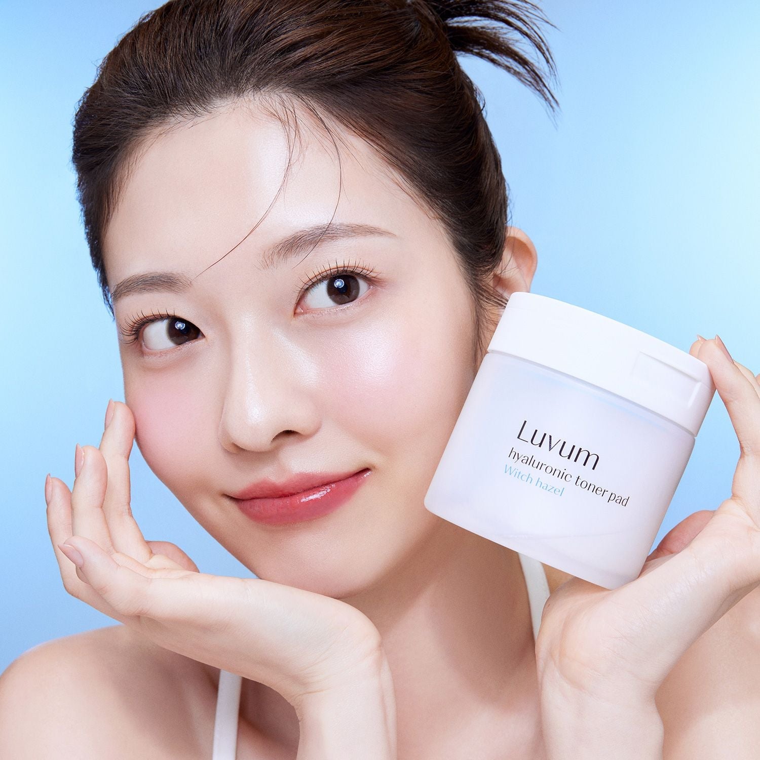 LUVUM 1 Hyaluronic Acid Toner Pads 60 Sheets : femme au visage lissant tenant le pot sur fond bleu