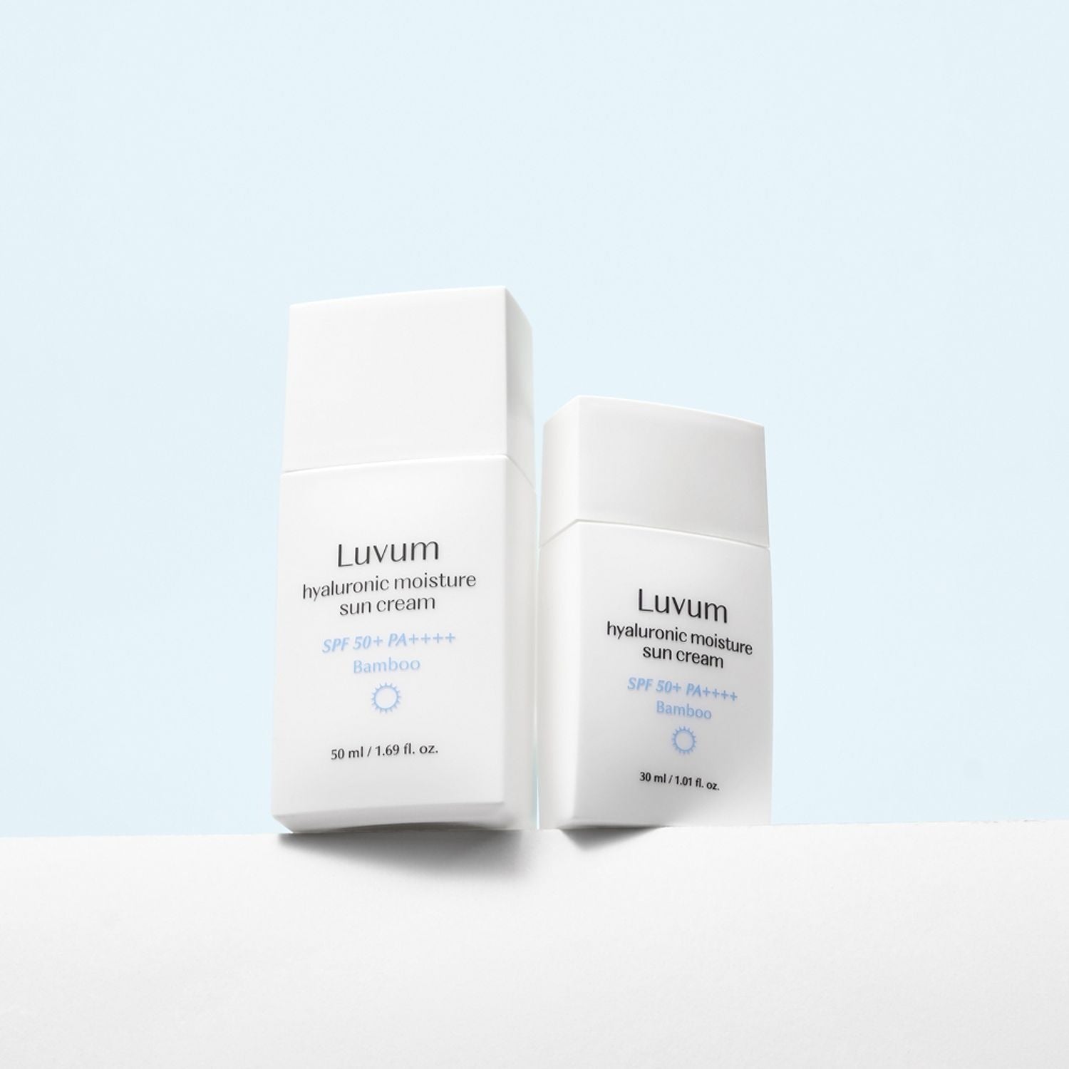 Décris l'image en français : LUVUM Bamboo Hyaluronic Acid Moisture Sunscreen 30ml sur fond bleu, boîtes et crème photo produit.