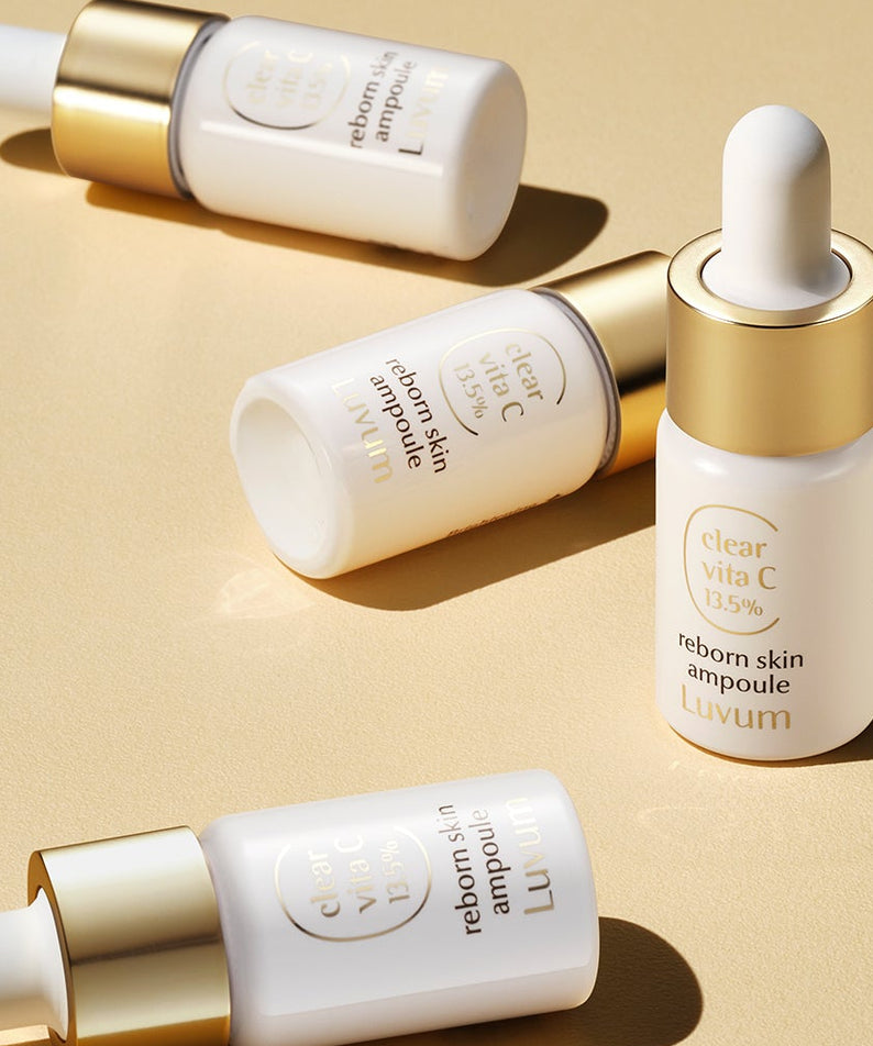 LUVUM Clear Vita C Ribbonn Skin Ampoule 10ml x3, flacons dorés et blancs sur fond beige, marque Luvum, produit beauté.