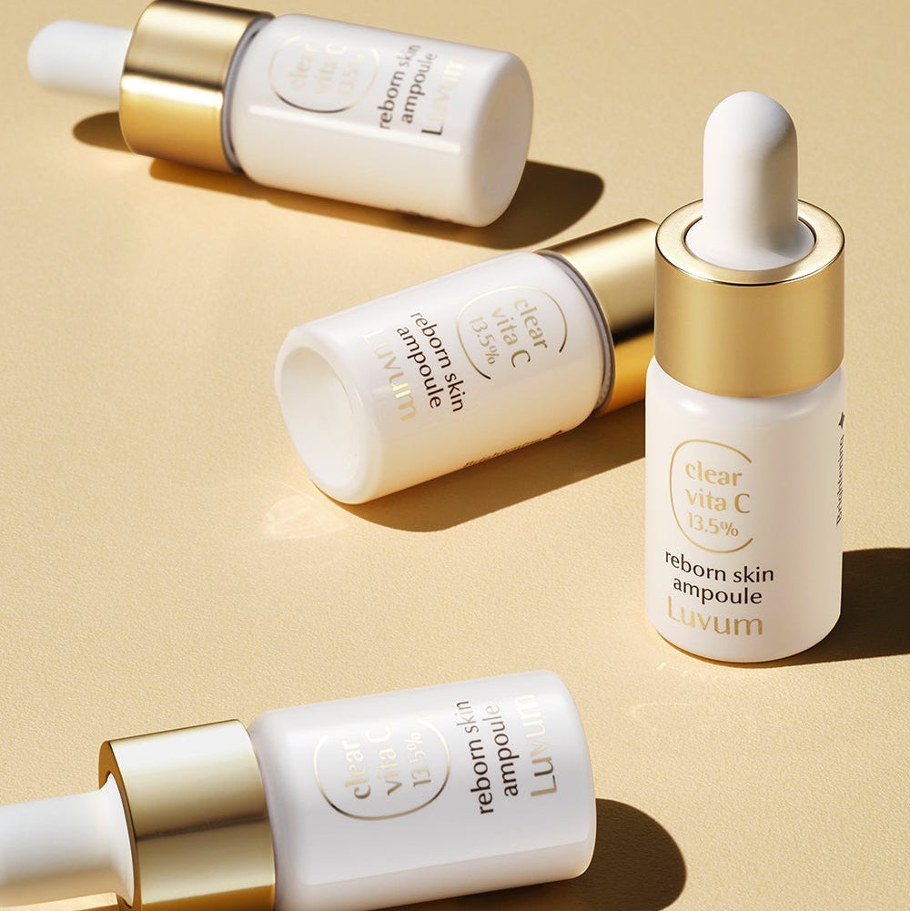LUVUM Clear Vita C Ribbonn Skin Ampoule 10ml x3, flacons dorés et blancs sur fond beige, marque Luvum, produit beauté.