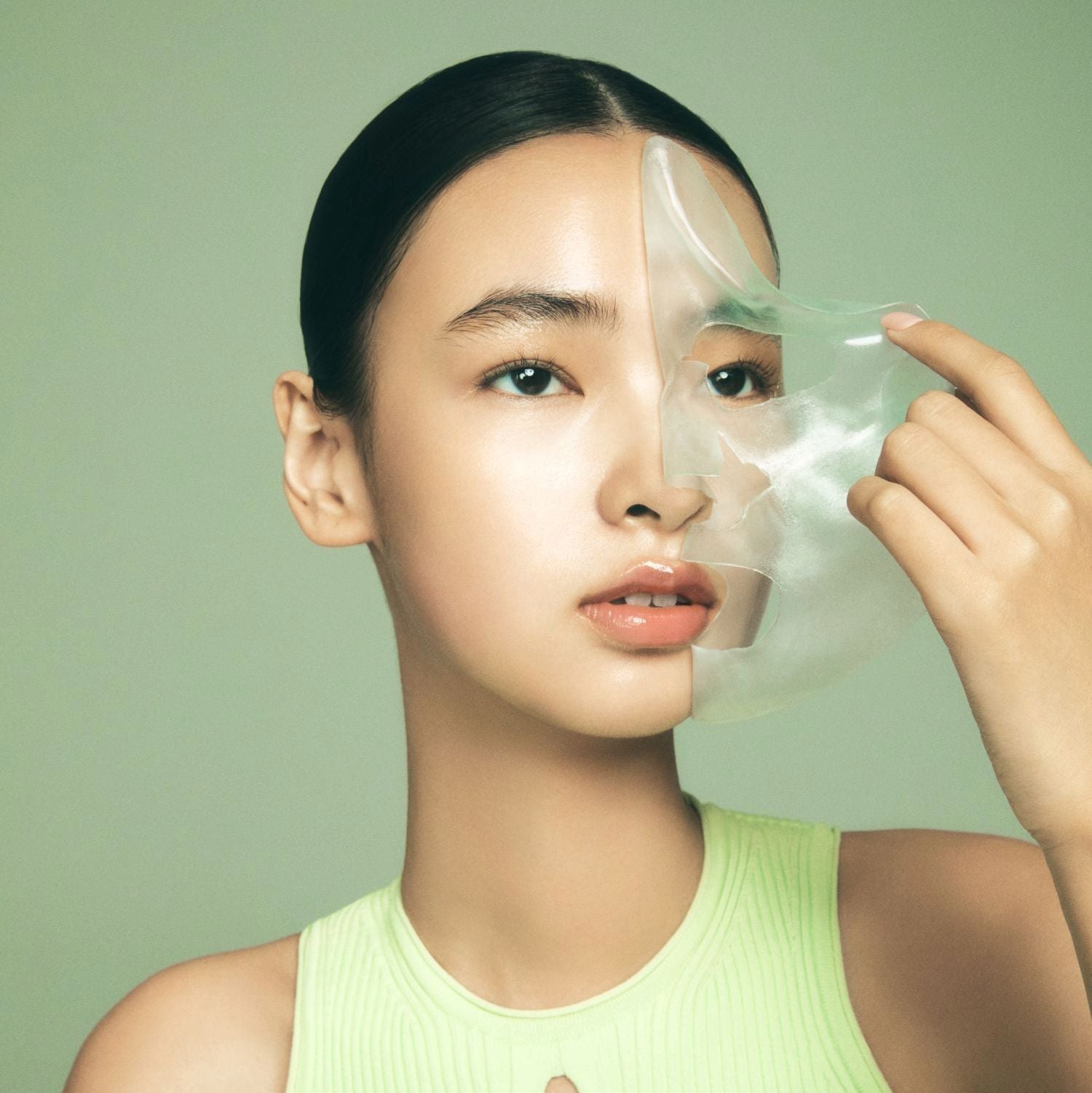 LUVUM Green Citrus Vitamin C Gel Mask Plus 5 Sheets, marque LUVUM : jeune femme applique un masque gel vert sur visage.