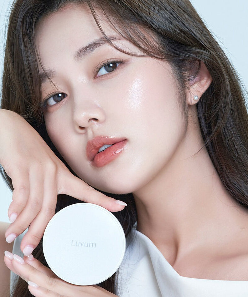 Décris l'image en français : LUVUM Moisture Glow Cushion Refill Set de Luvum, poudrier blanc tenu par une femme en gros plan.