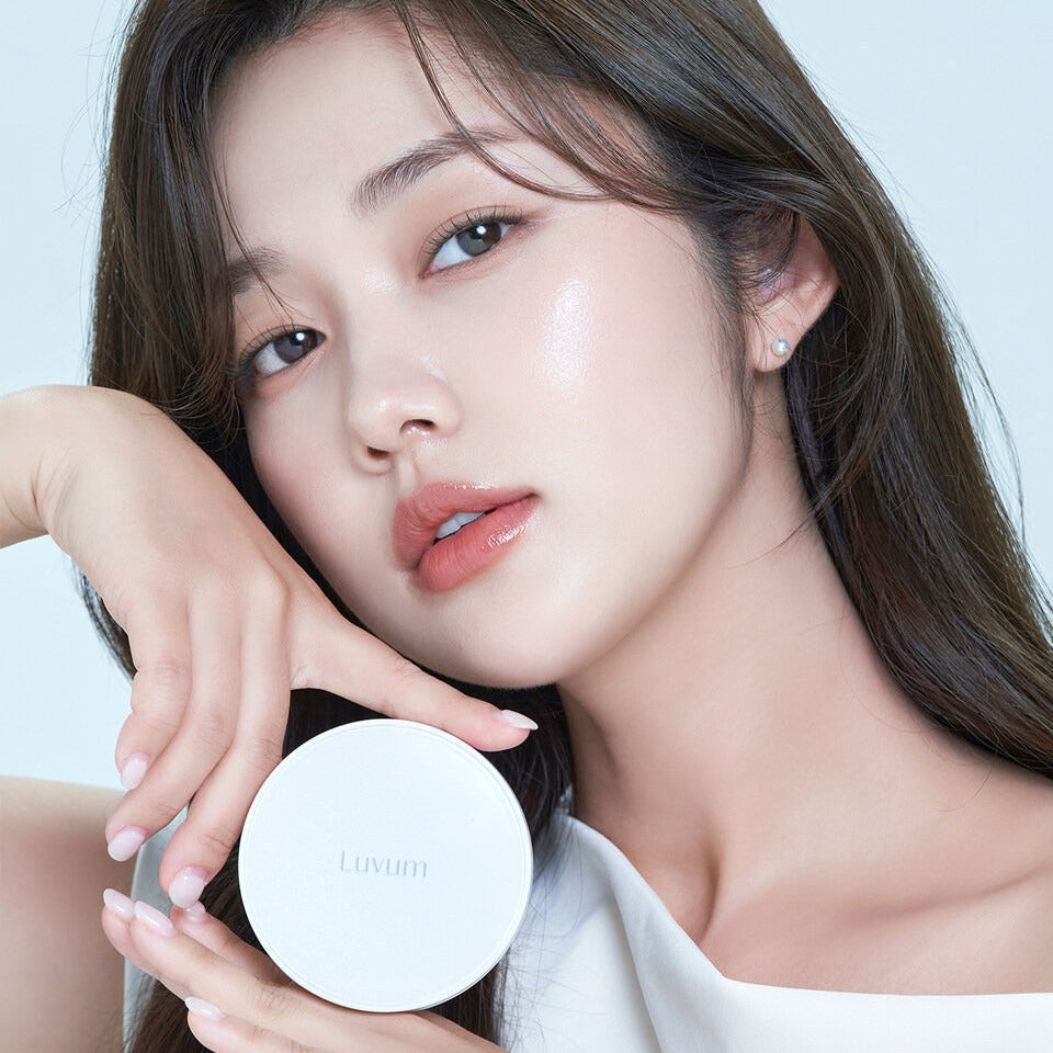 Décris l'image en français : LUVUM Moisture Glow Cushion Refill Set de Luvum, poudrier blanc tenu par une femme en gros plan.