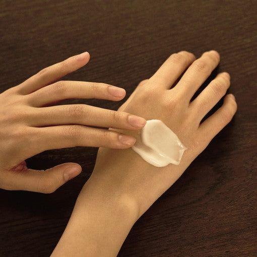 LUVUM Woody Rose Perfume Hand Cream 50ml, crème sur les mains, sur fond bois; marque LUVUM en contexte soin.