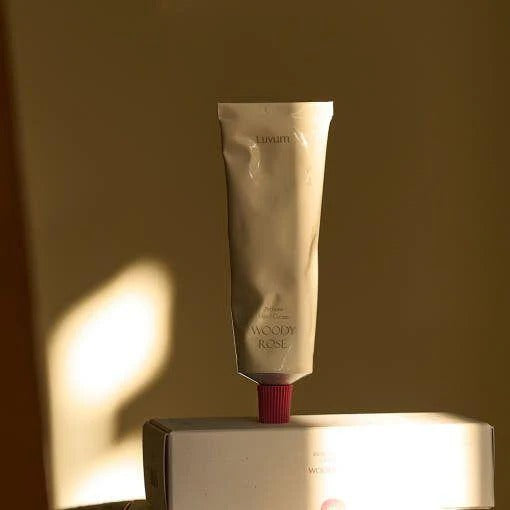 Décris l'image en français : LUVUM Woody Rose Perfume Hand Cream 50ml, tube crème main sur coffret, fond beige.