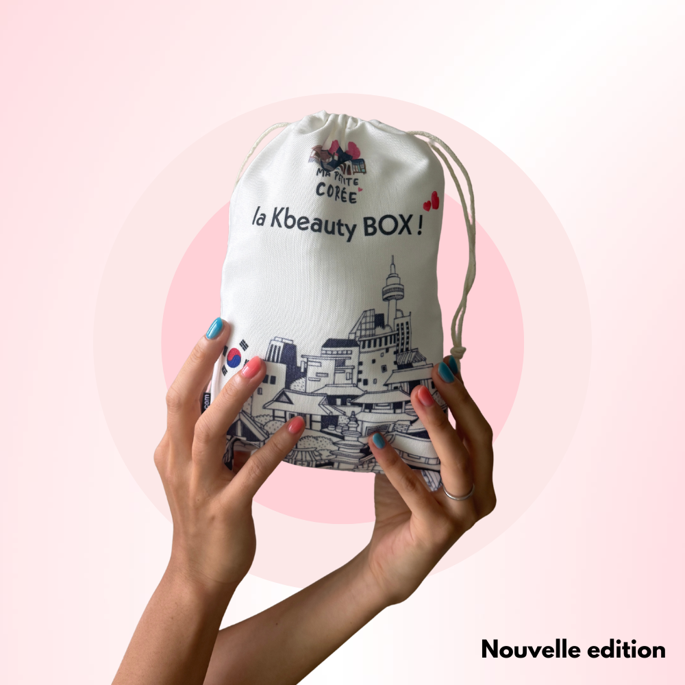 La K-beauty Box - Nouvelle edition : mains tenant un sac La Beauté Corée sur fond rose, visuel produit lifestyle.
