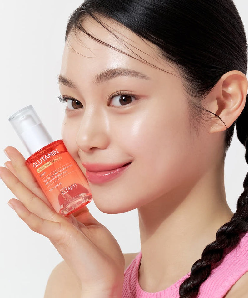 Décris l'image en français : MAKE P:REM Glutamine Antioxidant Radiance Serum 50ml, femme tenant le flacon sur fond blanc