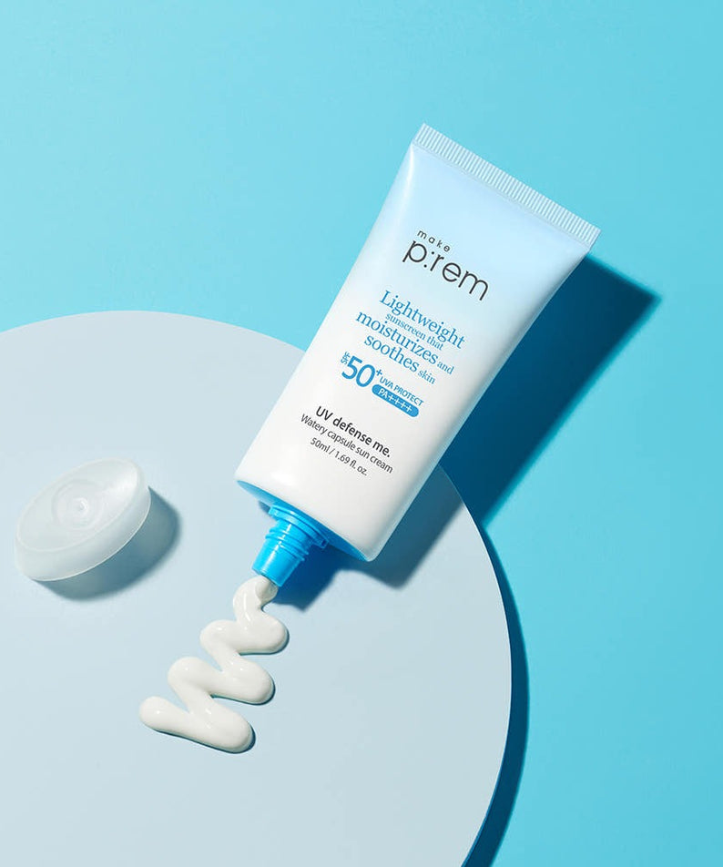MAKE P:REM UV Defense Me Watery Capsule Sunscreen 50ml SPF50+ PA++++, tube sur fond bleu, main/texture crème blanche